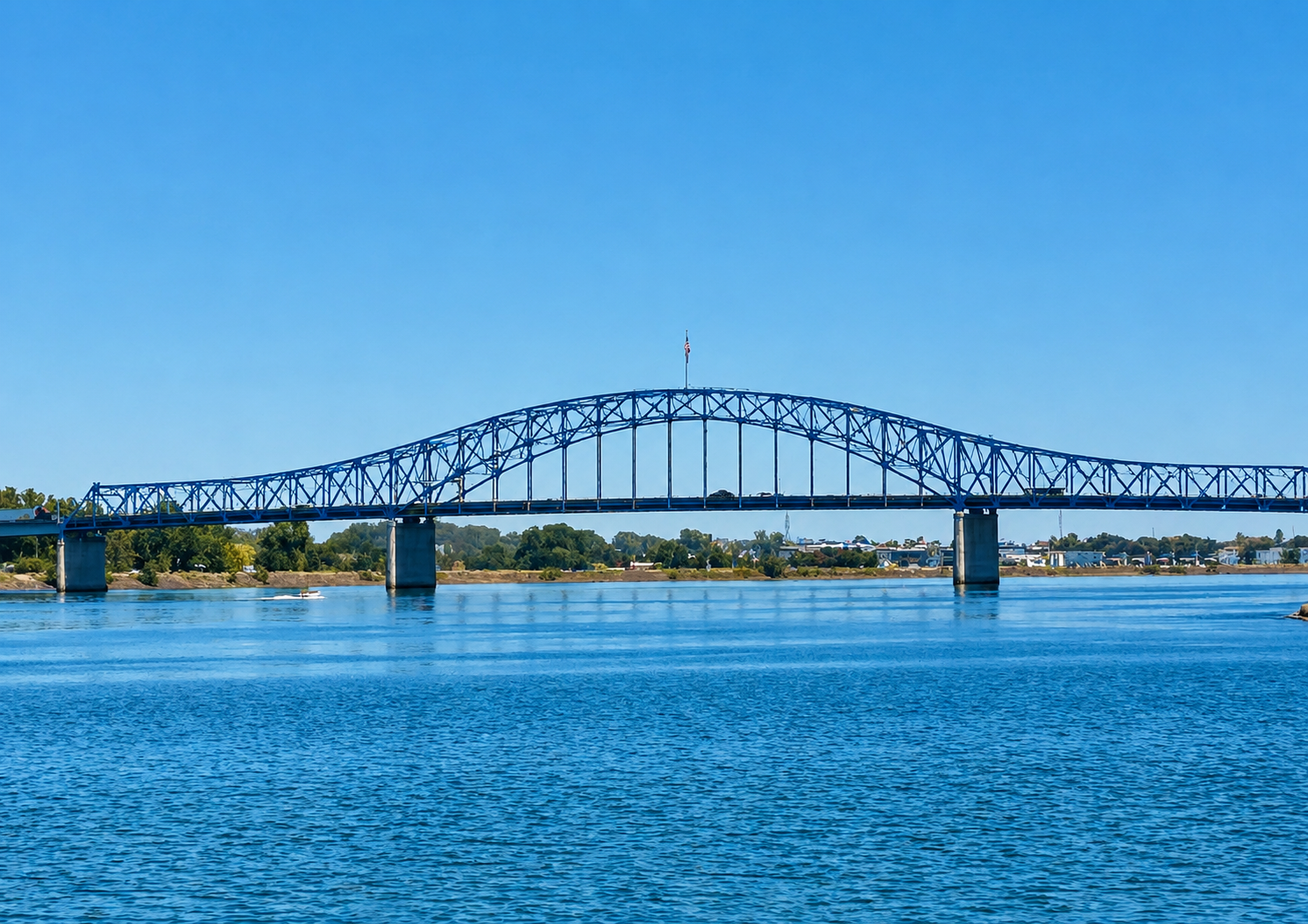 Blue steel truss bridge spanning the Columbia River under a clear sky in the Tri-Cities